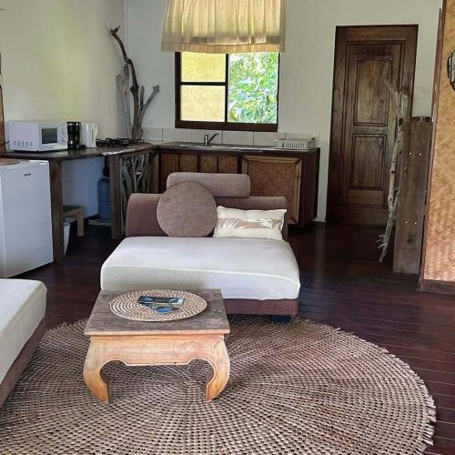 Petit aperçu du salon du bungalow Hanamio Hill avec une partie du lit et de la cuisine depuis la terrasse