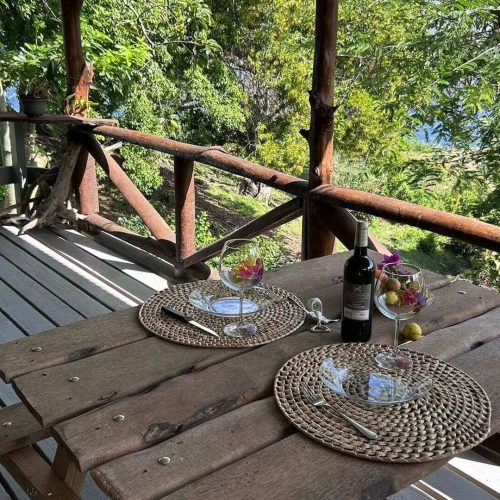 Vue depuis la terrasse du bungalow Hanamio Hill sur la table à manger, la verdure et la mer