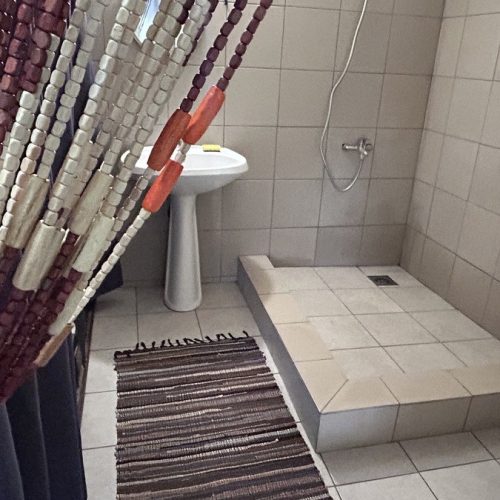 Salle de bain du bungalow Hanamio Hill avec douche italienne et lavabo vue depuis l’entrée