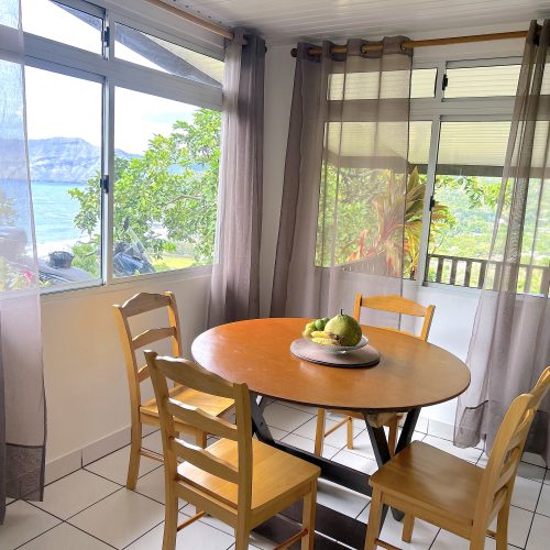 Coin repas intérieur avec table ronde et quatre chaises dans le logement Katu Home à Hiva Oa.