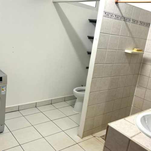 Grande salle de bain de Katu Home avec machine à laver, lavabo, WC et douche à l’italienne.