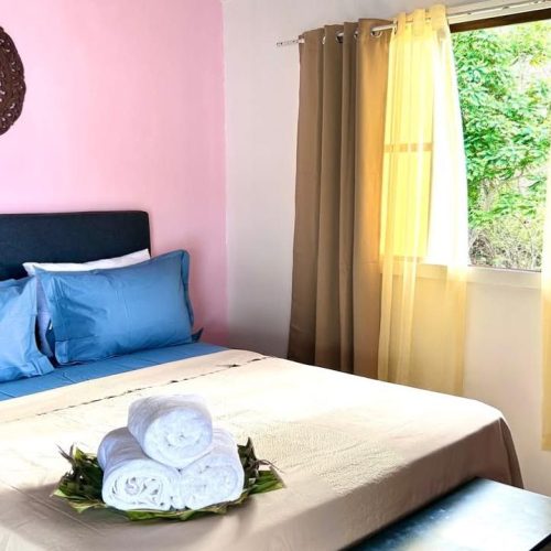 Lit du bungalow Hanamio Bay avec serviettes pliées, vue de face.