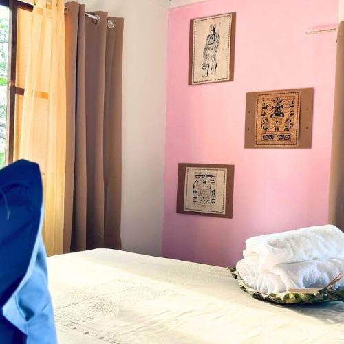 Vue arrière du lit king size de Hanamio Bay avec trois tapa décoratifs au mur.