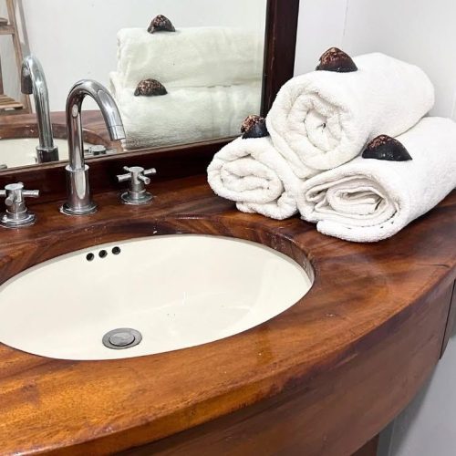 Lavabo en bois de la salle de bain Hanamio Bay avec serviettes enroulées.