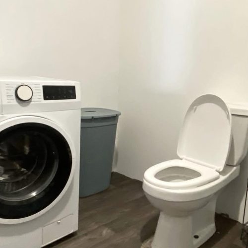 Salle de bain du bungalow Hanamio Bay avec WC et machine à laver.